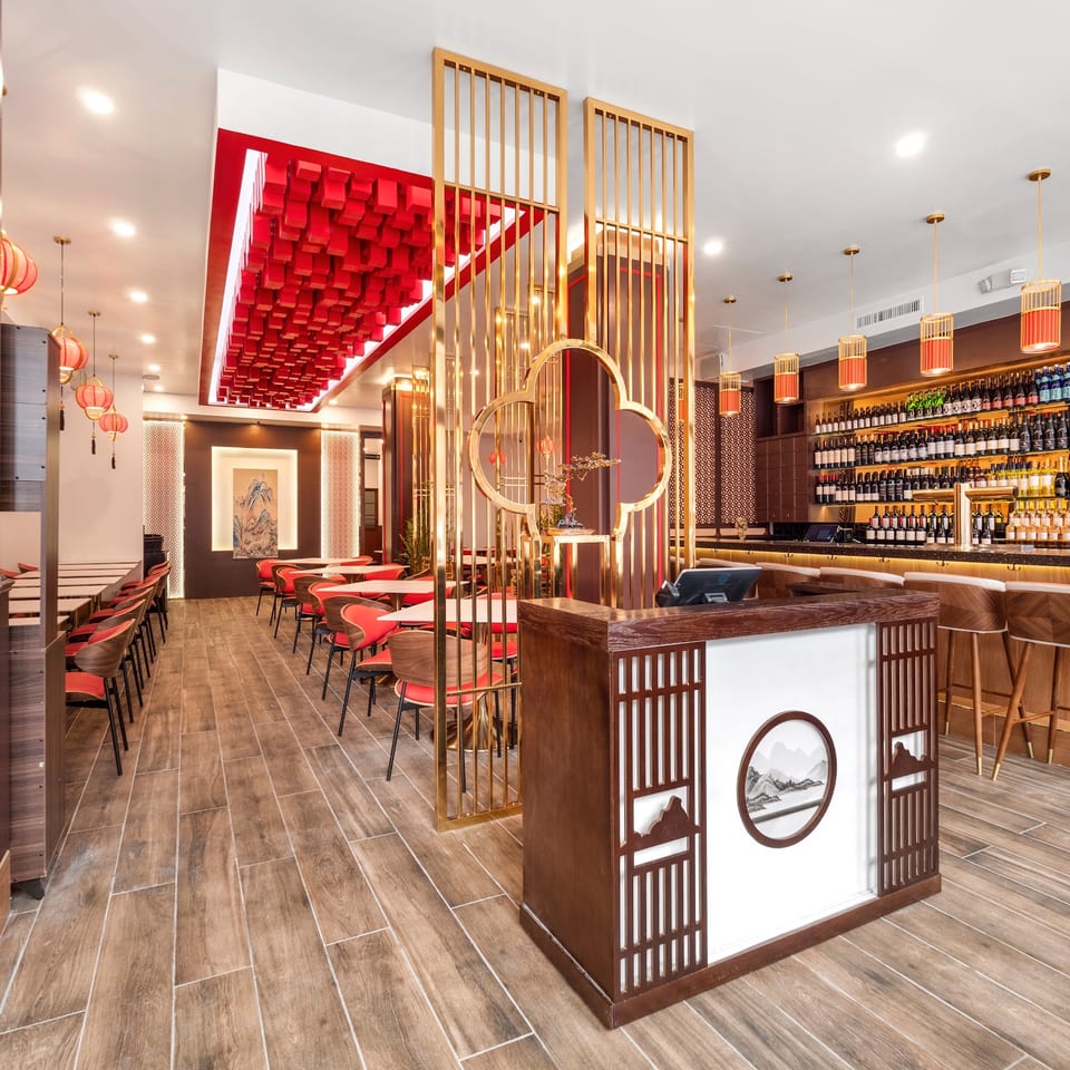A modern Chinese restaurant interior with red and gold accents, a bar, and dining tables.