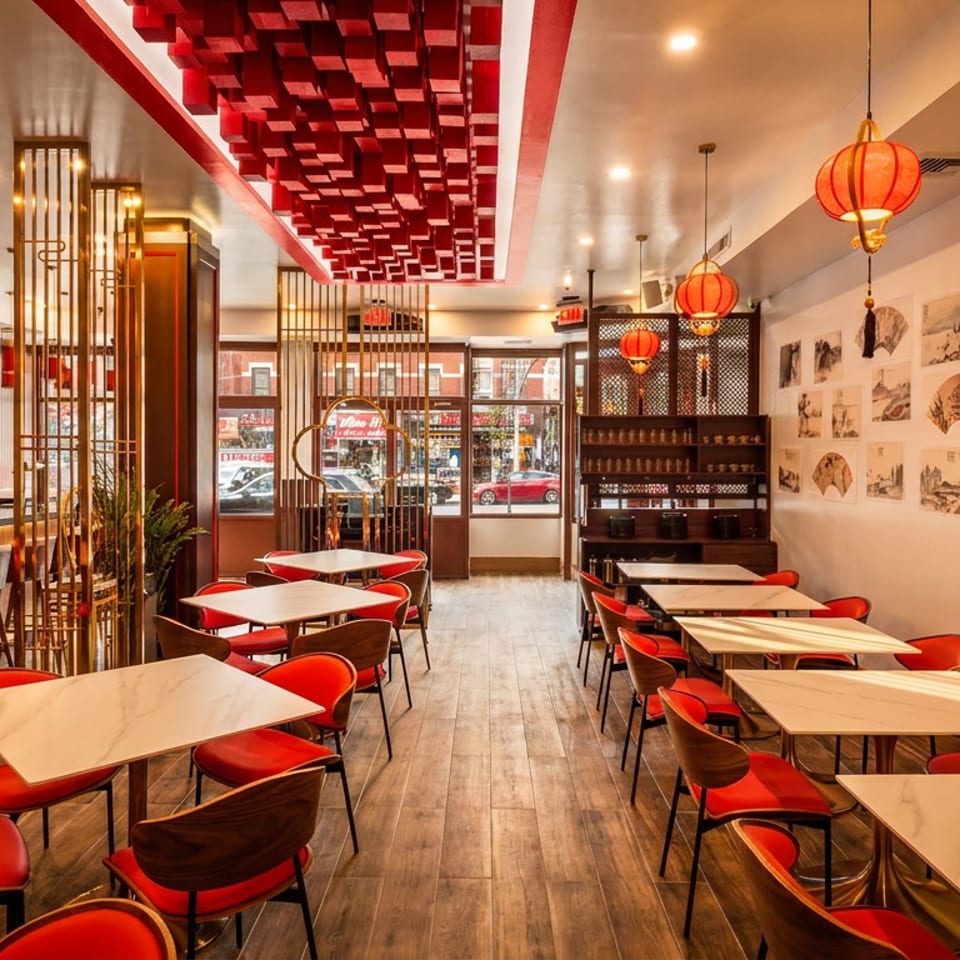 Restaurant interior with red chairs, white tables, a bar, and Asian-inspired decor with red lanterns.
